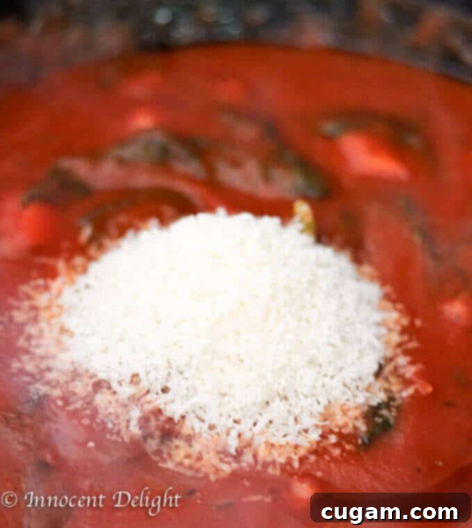 Blending Parmesan cheese into the simmering tomato basil sauce for a creamy texture.