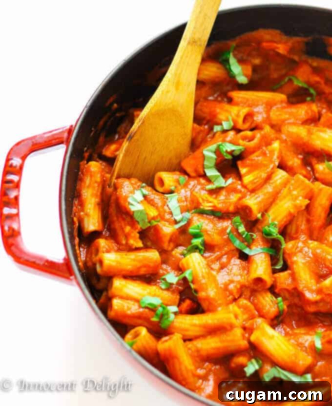 Close-up of Chicken Tomato Basil Rigatoni, ready to be served, topped with fresh basil and Parmesan.
