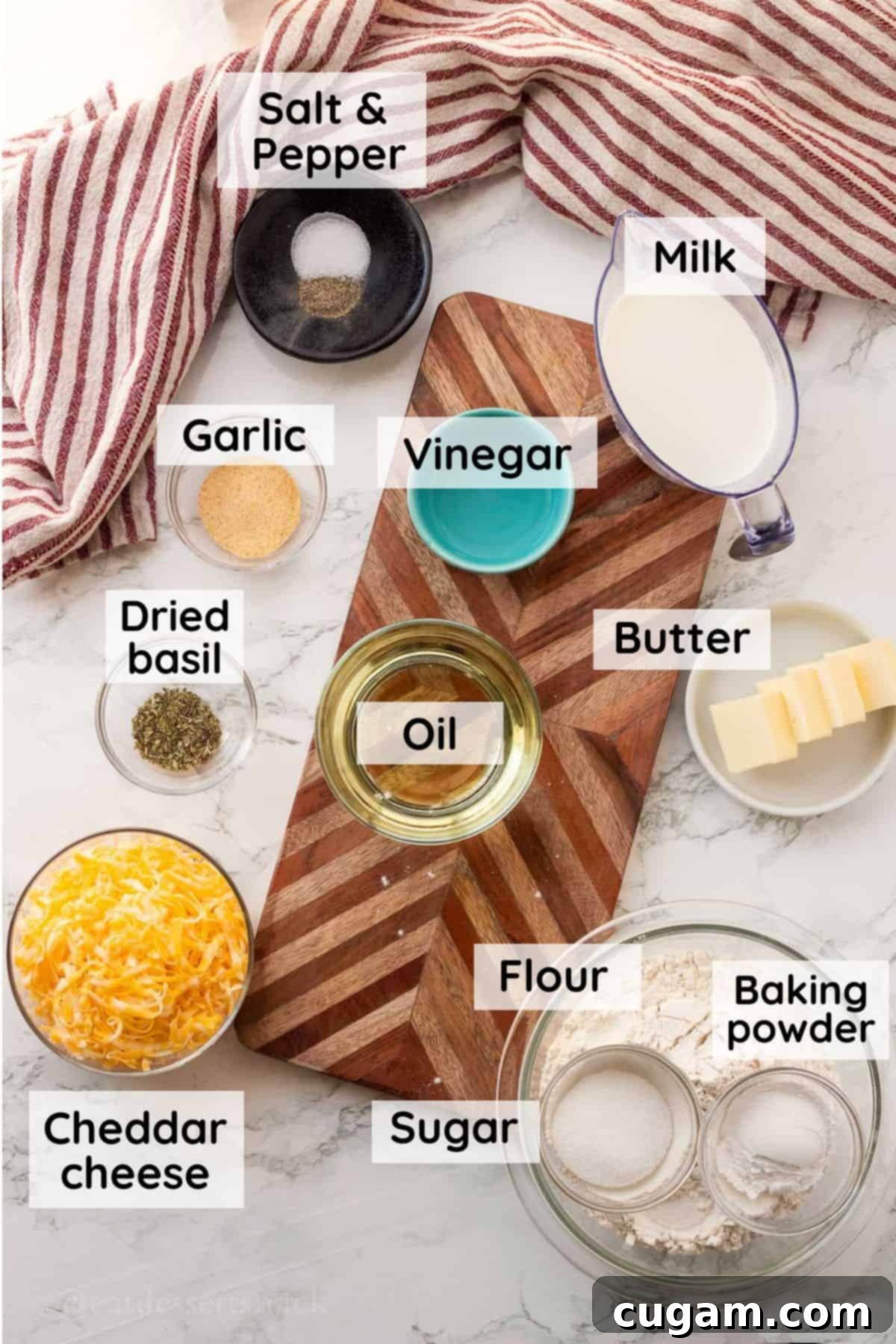 Labeled ingredients in glass bowls for garlic cheddar biscuits.