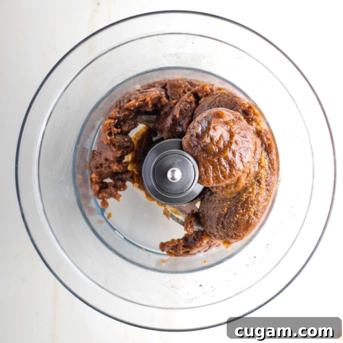 Dark brown mixture balled up in the bowl of a food processor.