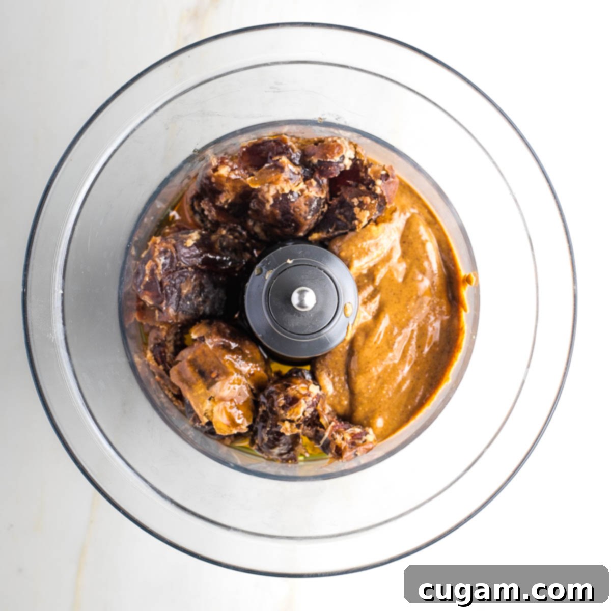 Almond butter, dates, maple syrup and olive oil in the bowl of a food processor. 