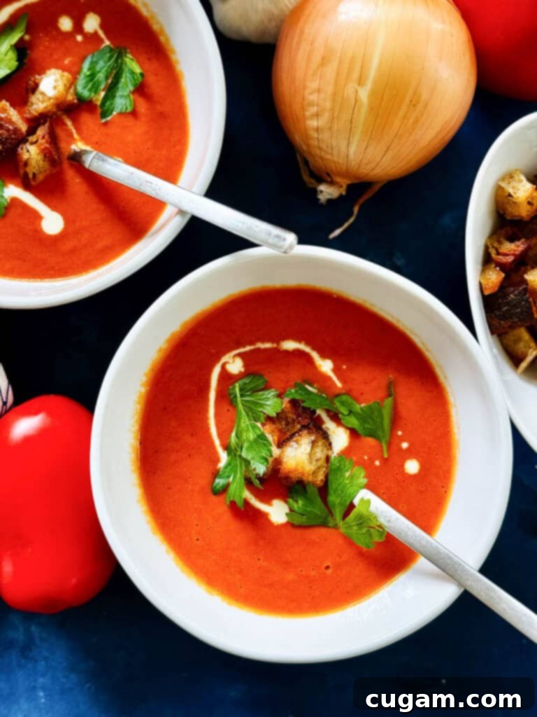 A comforting bowl of oven-roasted tomato soup garnished with fresh basil and a drizzle of cream.
