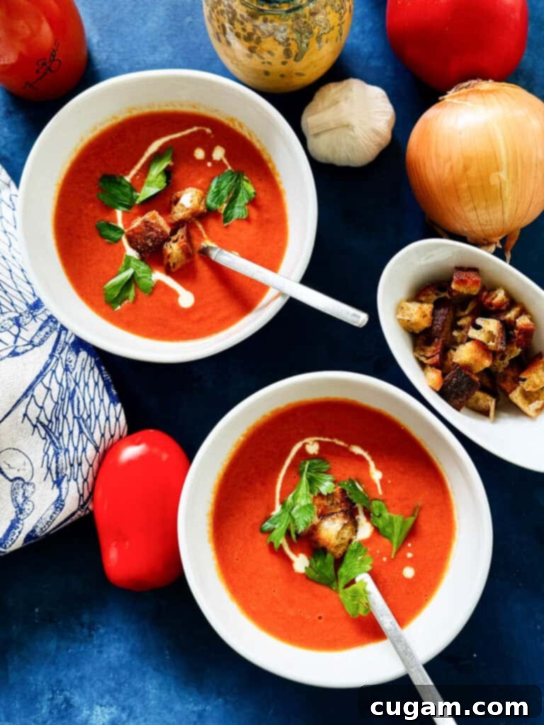 Two bowls of creamy oven-roasted tomato soup, each topped with golden homemade croutons and a drizzle of cream.