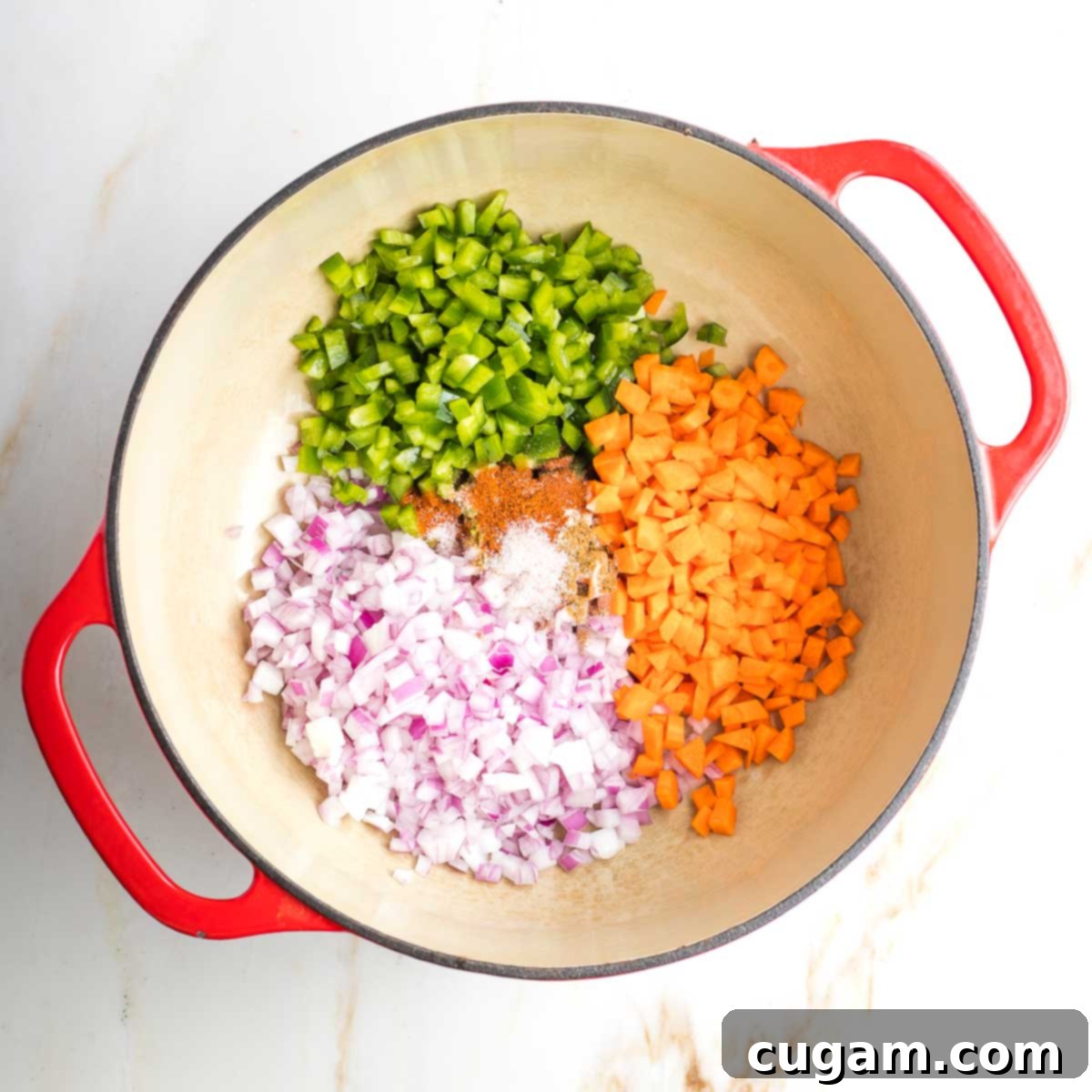 Dutch oven with sections of chopped onion, carrot and green pepper.