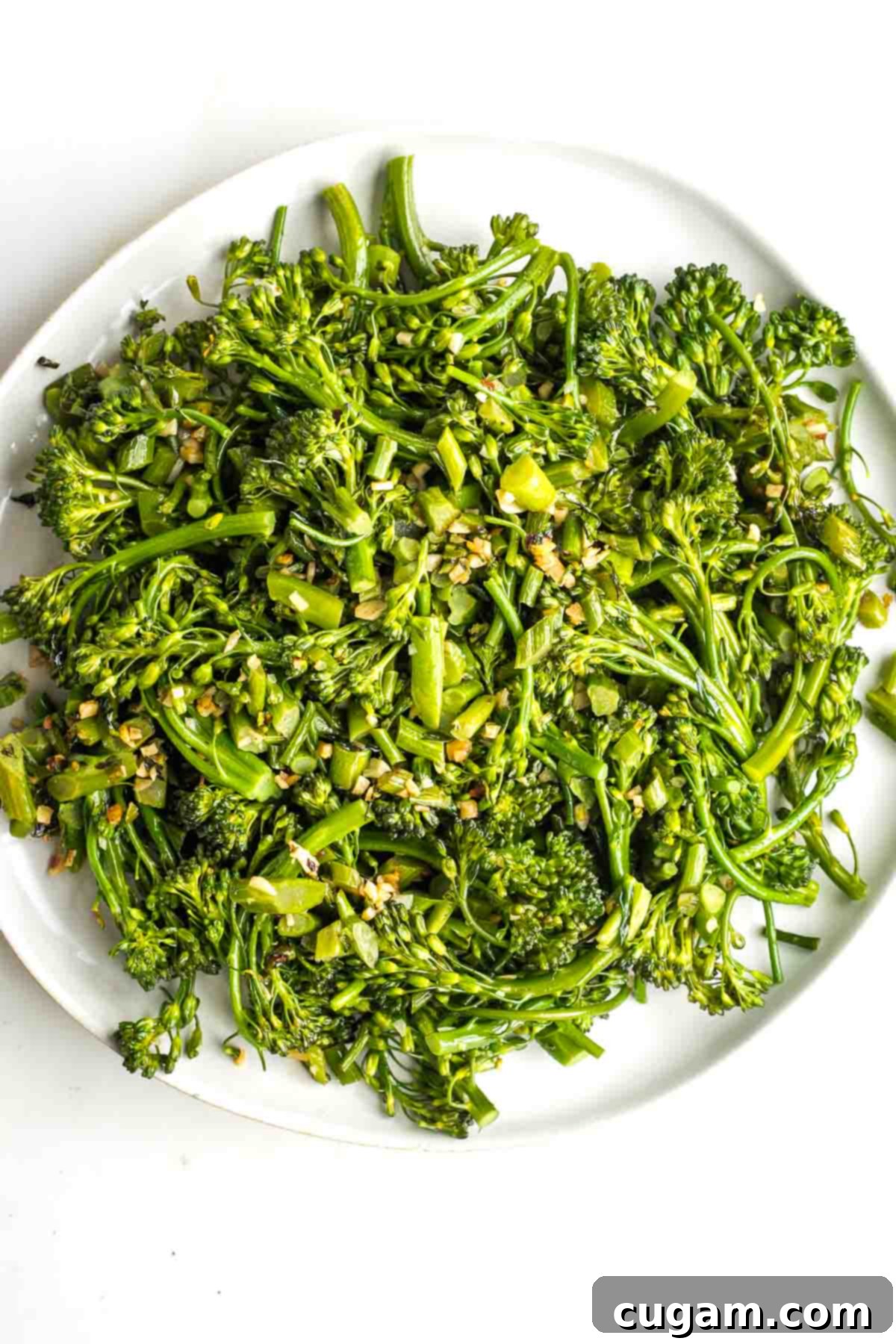 Sauteed baby broccoli and garlic with crushed red pepper on a white platter. 