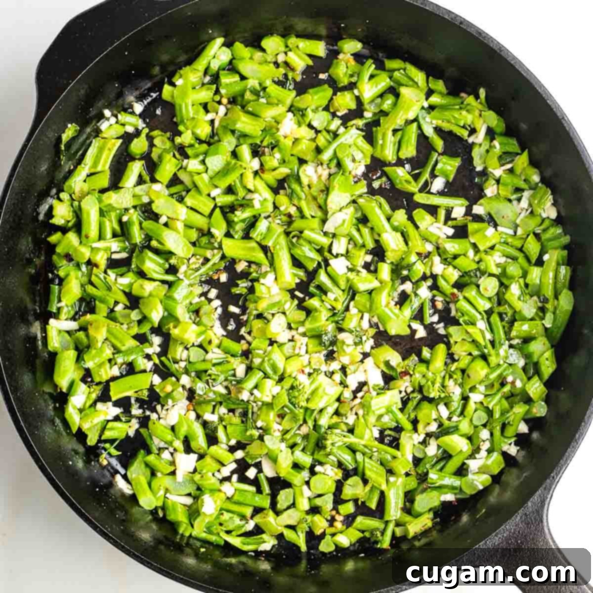 Chopped baby broccoli stems in a cast iron skillet with minced garlic. 