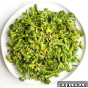 Plate filled with cooked baby broccoli with pieces of garlic.