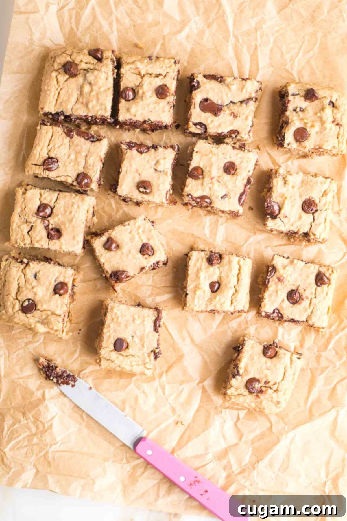 White bean blondies with chocolate chips, cut into squares with a pink knife. 