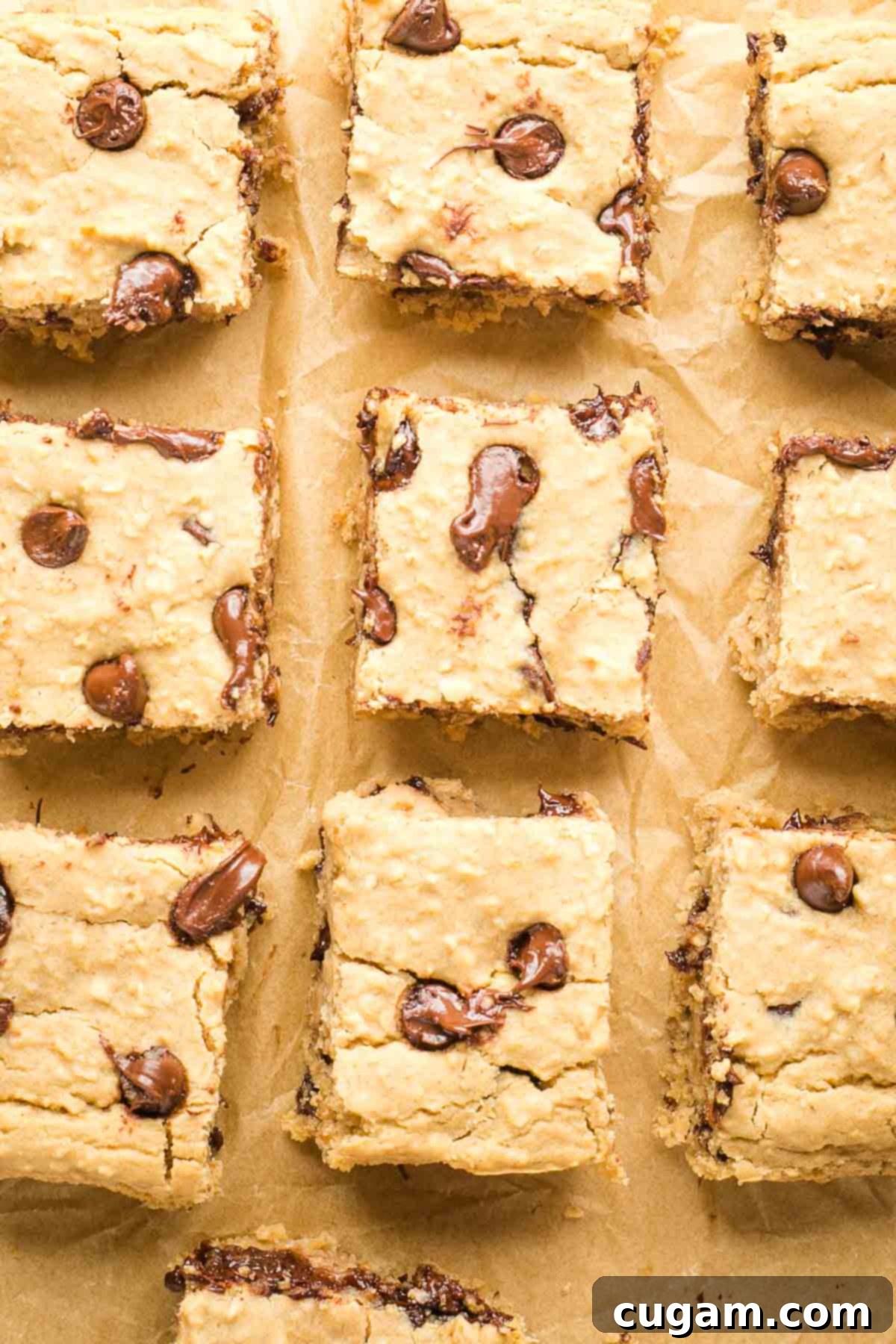 Squares of chocolate chip blondies on a piece of unbleached parchment paper.