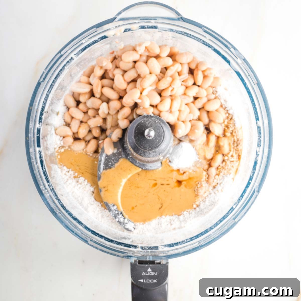 Food processor bowl withwhite beans, flour, tahini, baking powder and syrup.