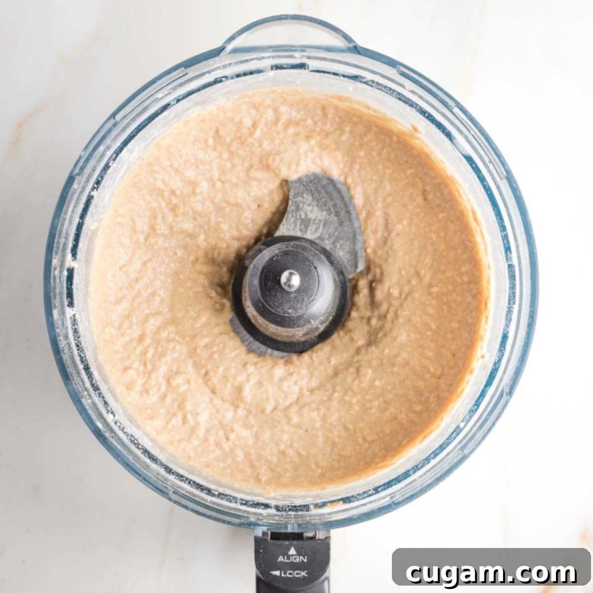 Light colored cookie batter in the bowl of a food processor. 