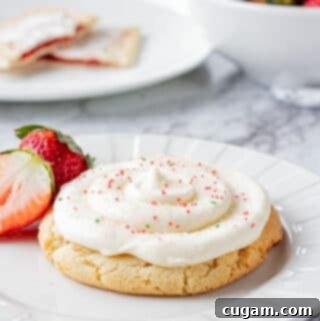 Baked strawberry poptart sugar cookie on a white plate with strawberries.