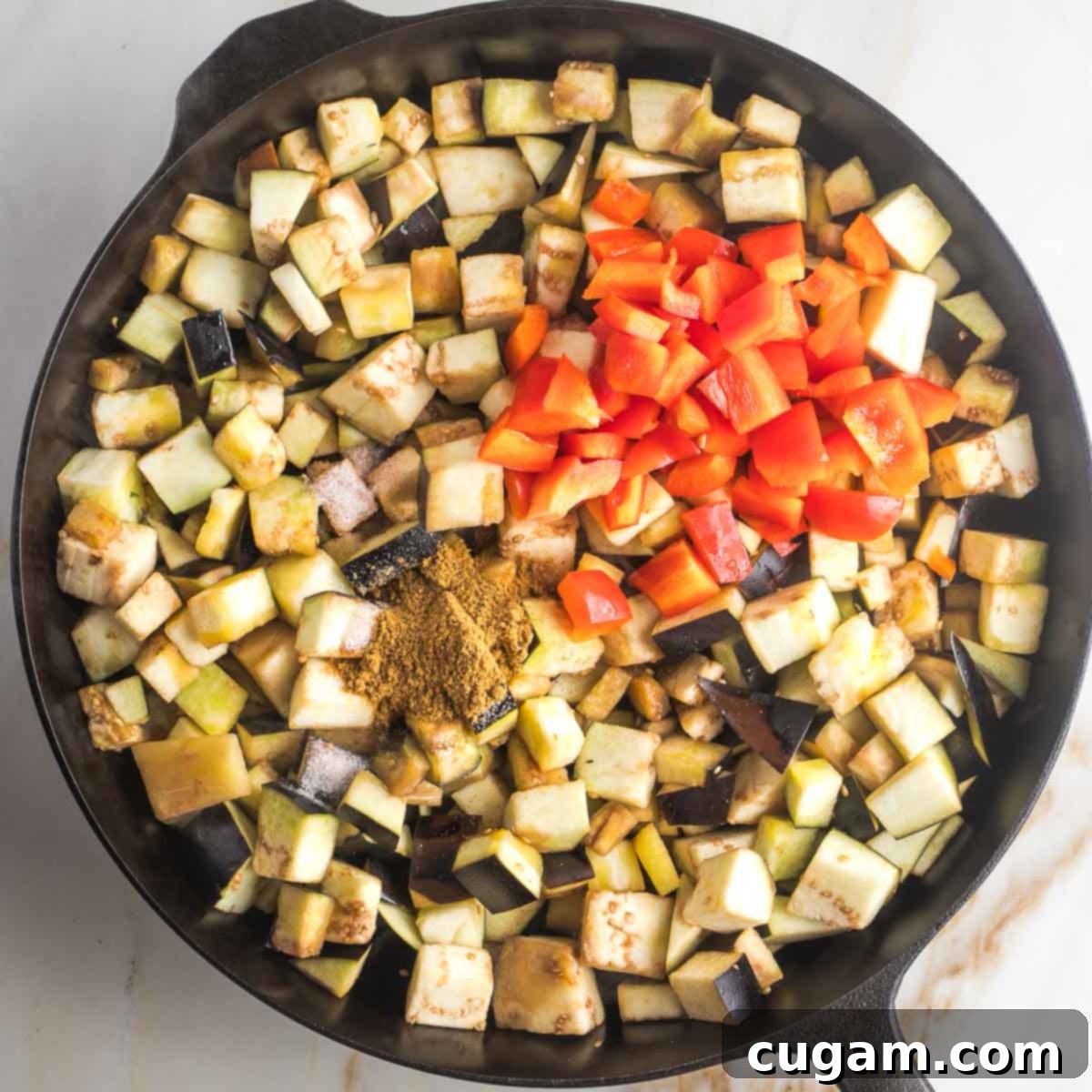 Pan-Fried Eggplant Salad 11 Sautéing eggplant cubes with diced red peppers and a heap of cumin in a cast iron skillet, mid-cooking process.