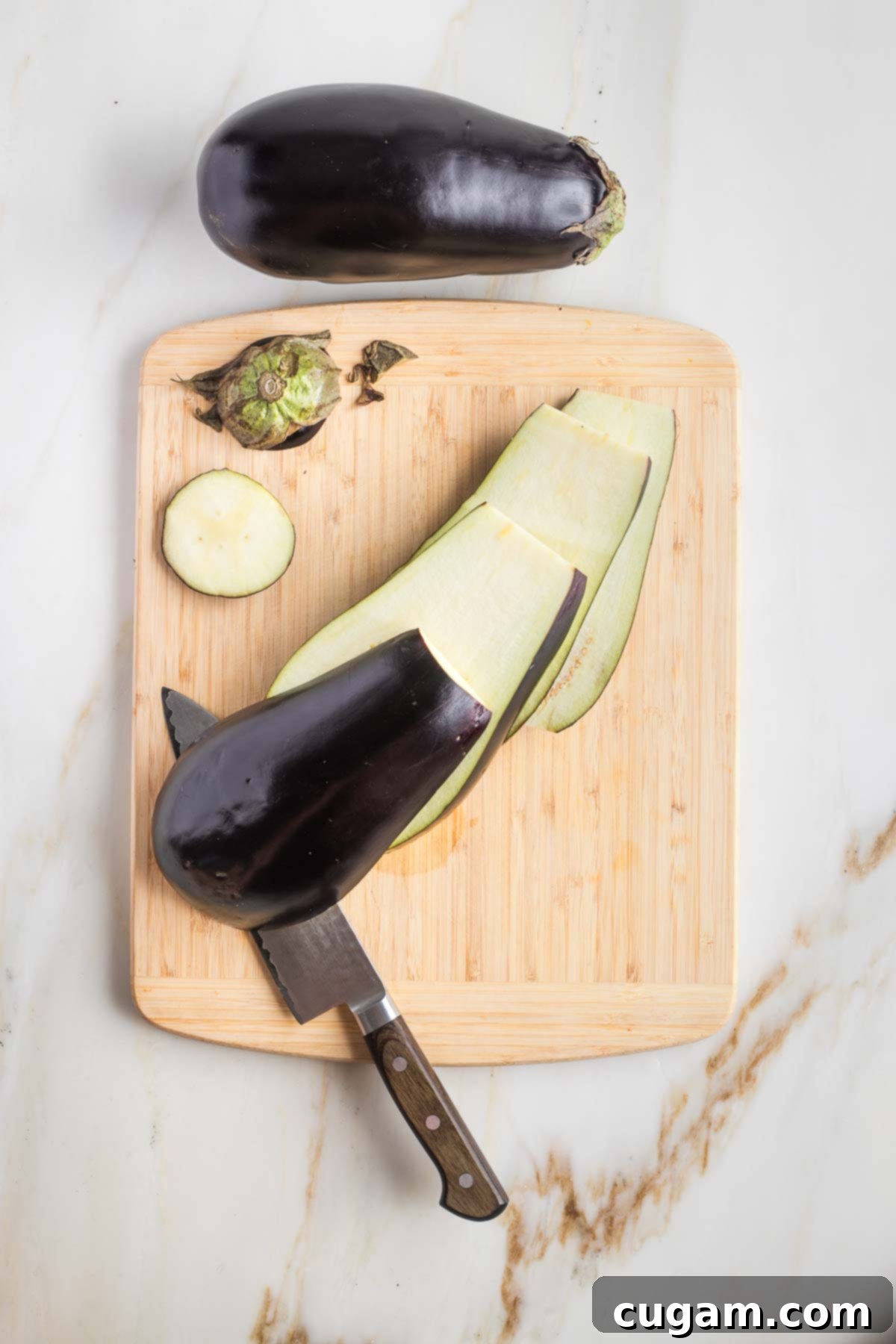 Pan-Fried Eggplant Salad 4 An eggplant with its top and tail removed, placed cut side down on a cutting board, ready for slicing.