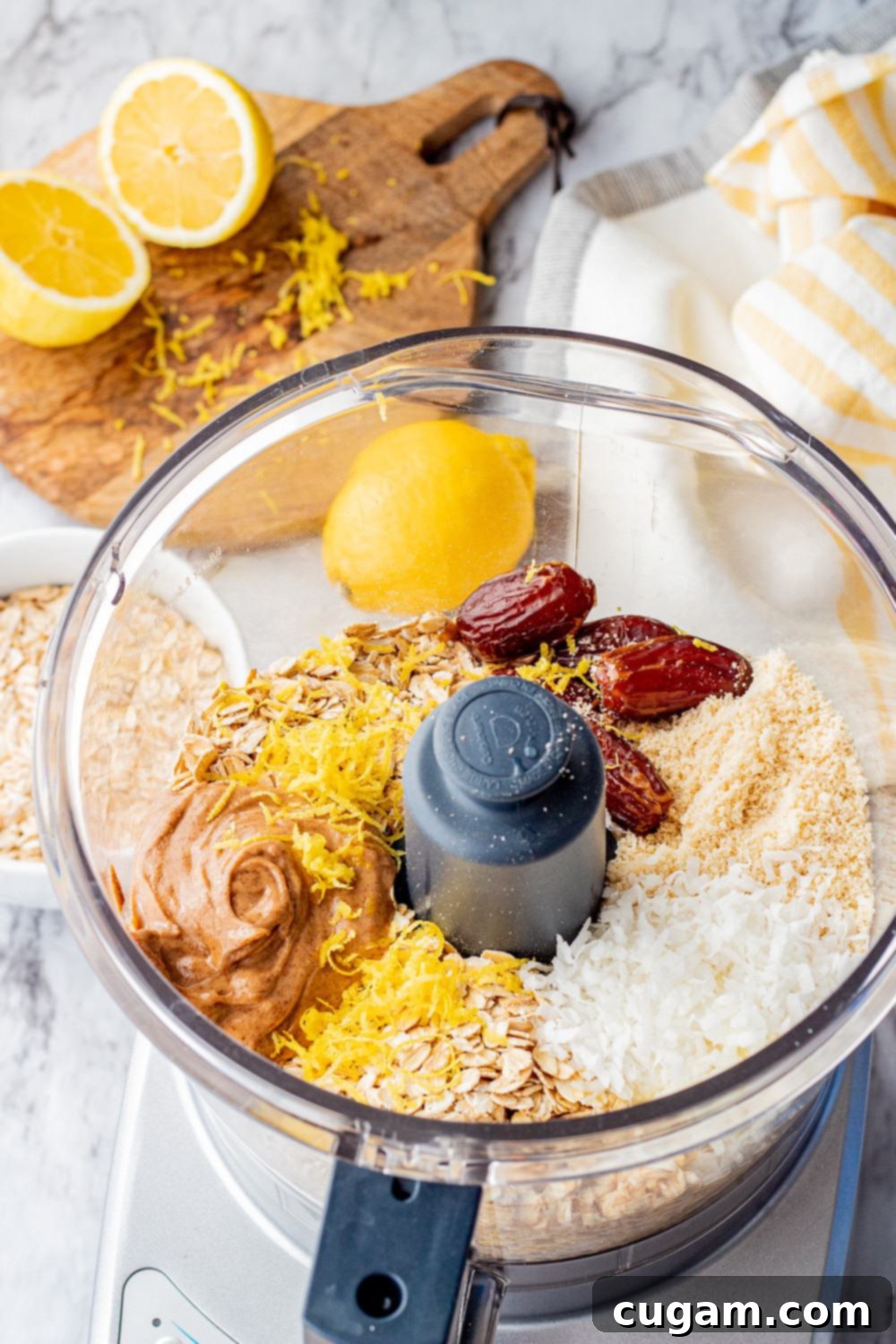 Lemon coconut protein balls are no bake energy balls with dates, oats, almond butter, almond flour, coconut, lemon, and protein powder. #proteinballs #energy bites clear plastic bowl with dates, almond butter, almond flour, coconut flakes, oats, lemon zest and juice, and vanilla extract.