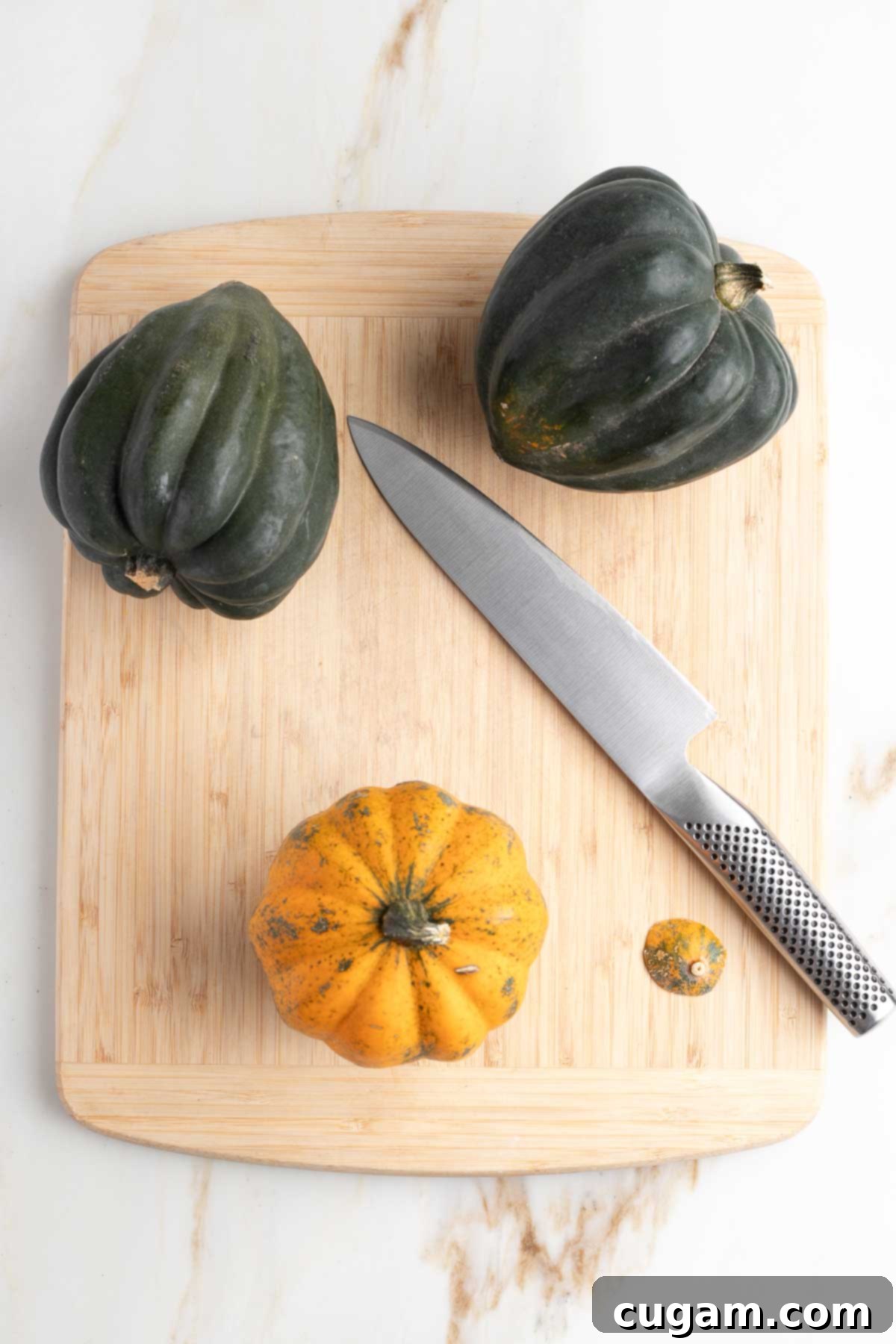 Three acorn squash on a cutting board, one with a sliver cut off bottom, it's standing upright.