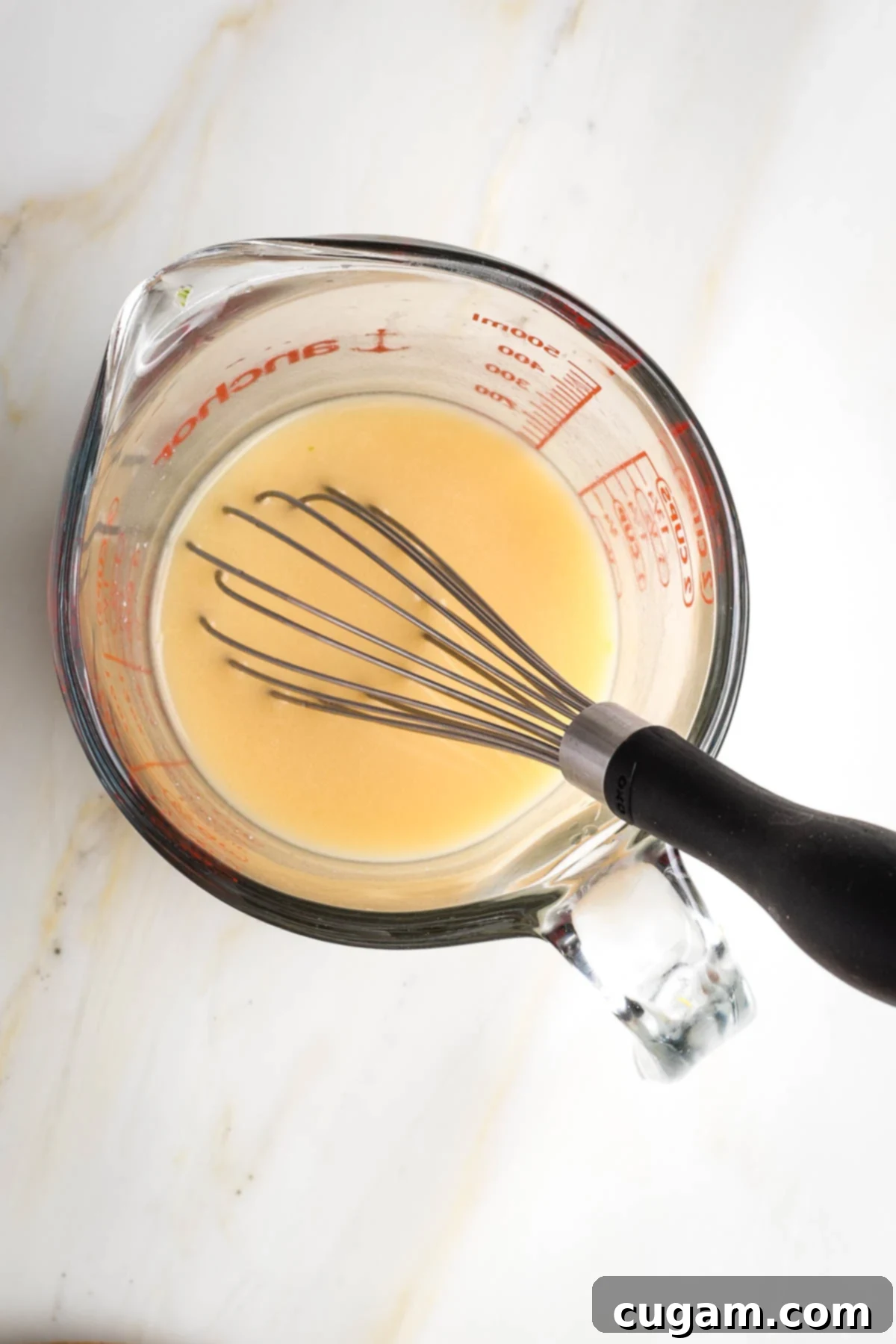 Whisking miso with hot water in a pyrex liquid measuring cup. 