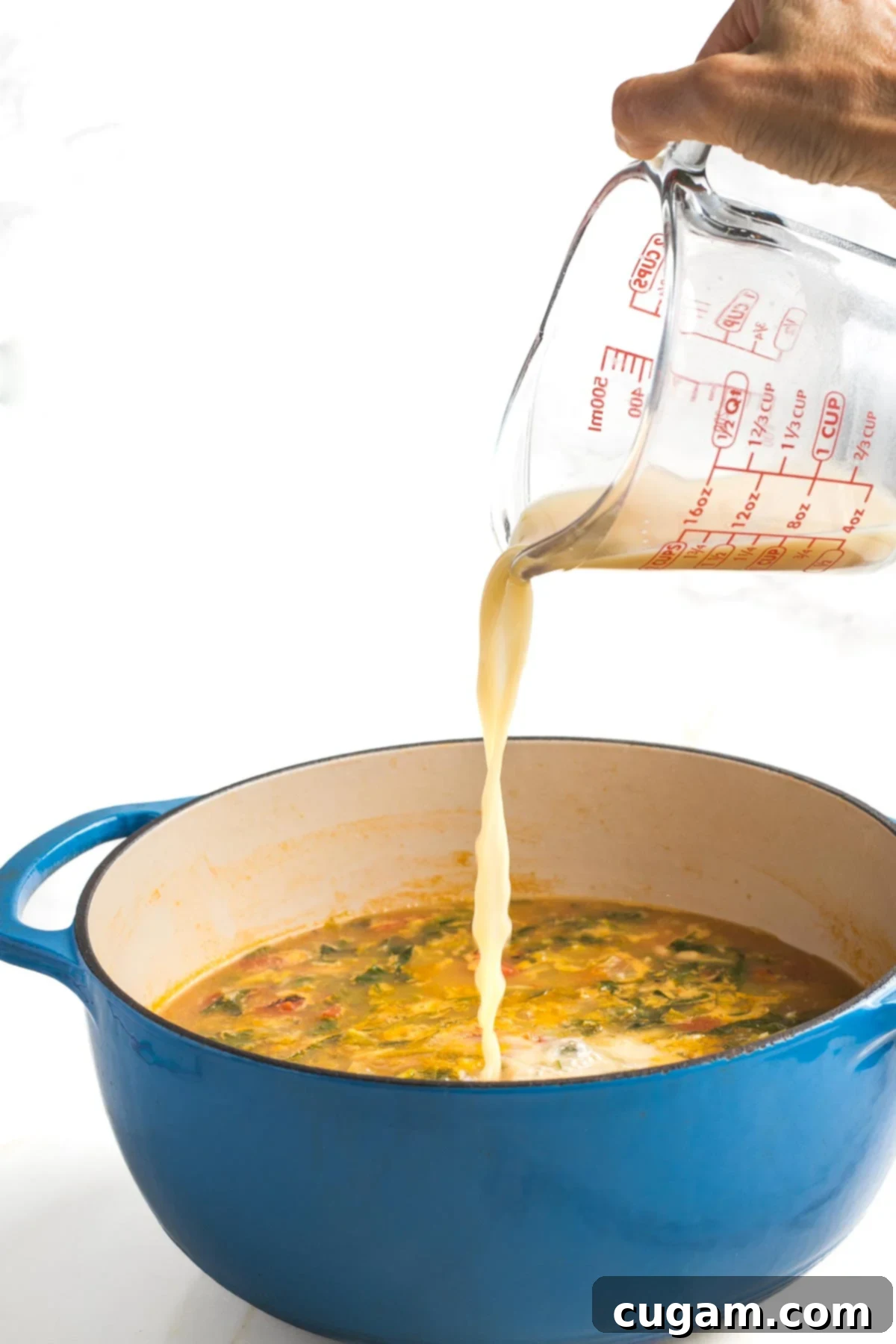 Pouring miso slurry into pot of escarole bean soup. 