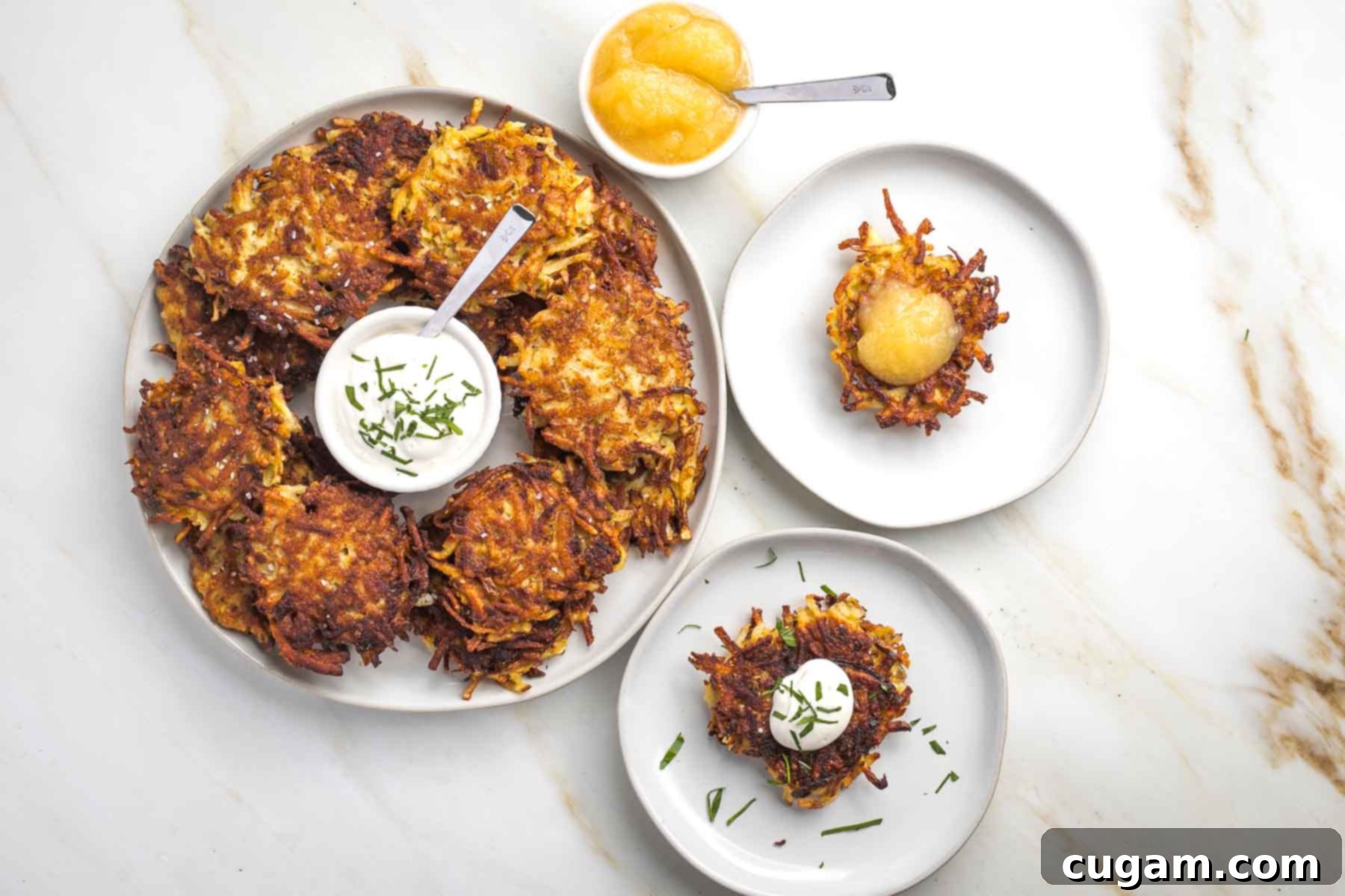Grandma's Secret Potato Latkes 15 Platter of latkes with sour cream in the center, plus a small dish of applesauce and small plates with latkes.