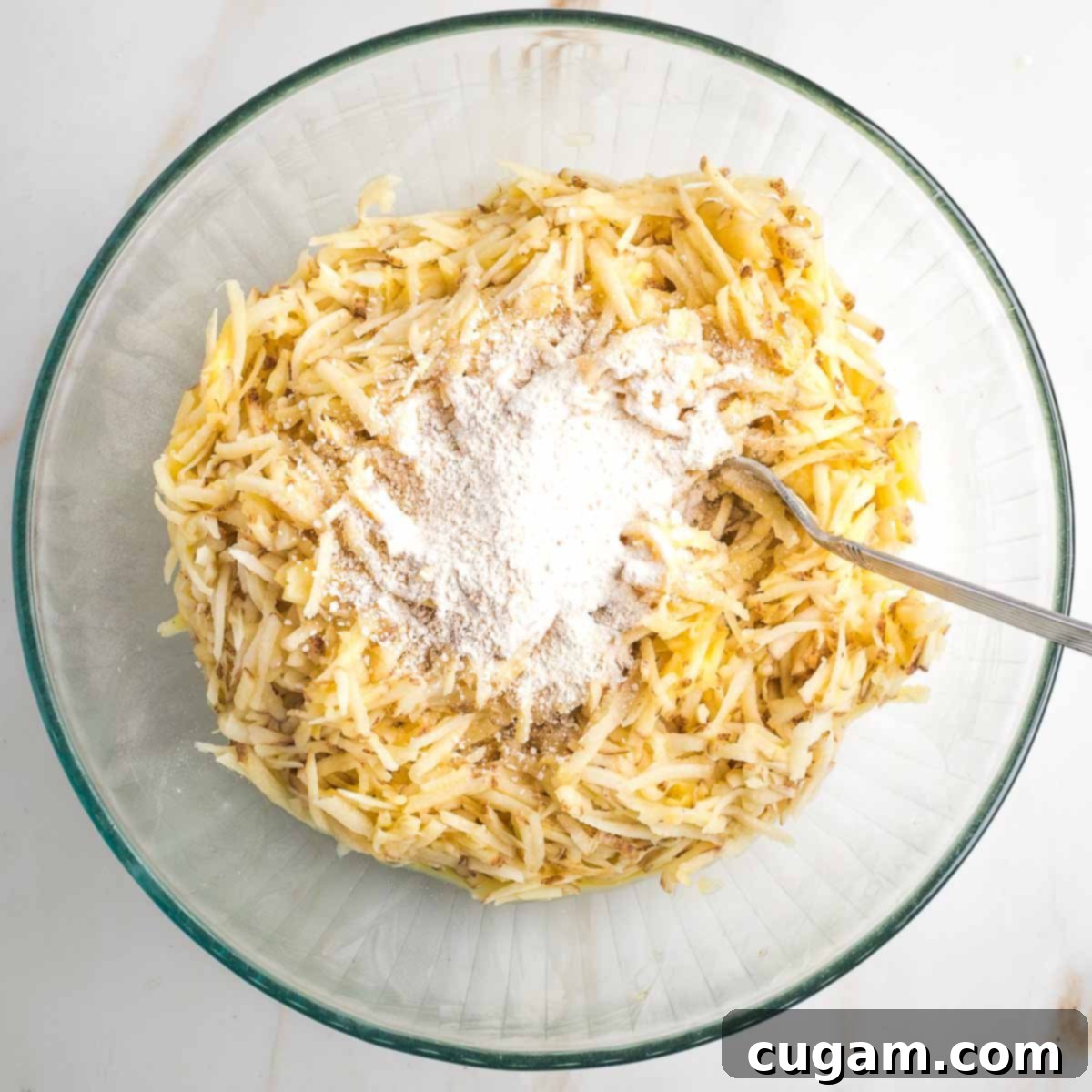 Grandma's Secret Potato Latkes 8 Shredded potatoes in a bowl with some matzo meal on top.