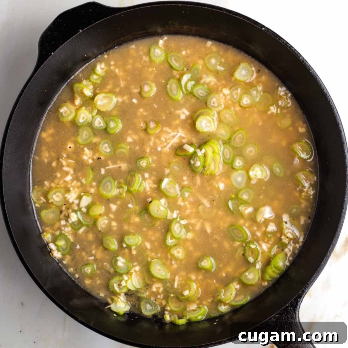 Vegetable broth and miso being whisked together and added to the skillet.