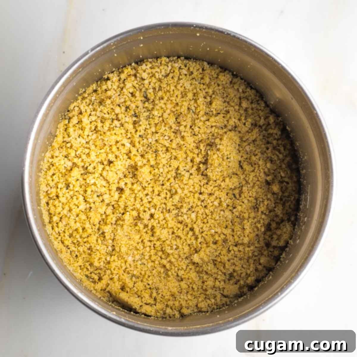 Spice grinder container with crumbly yellow mixture.