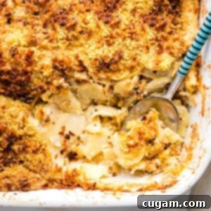 Parsnip gratin in a white baking dish, a spoon scooping out a portion.
