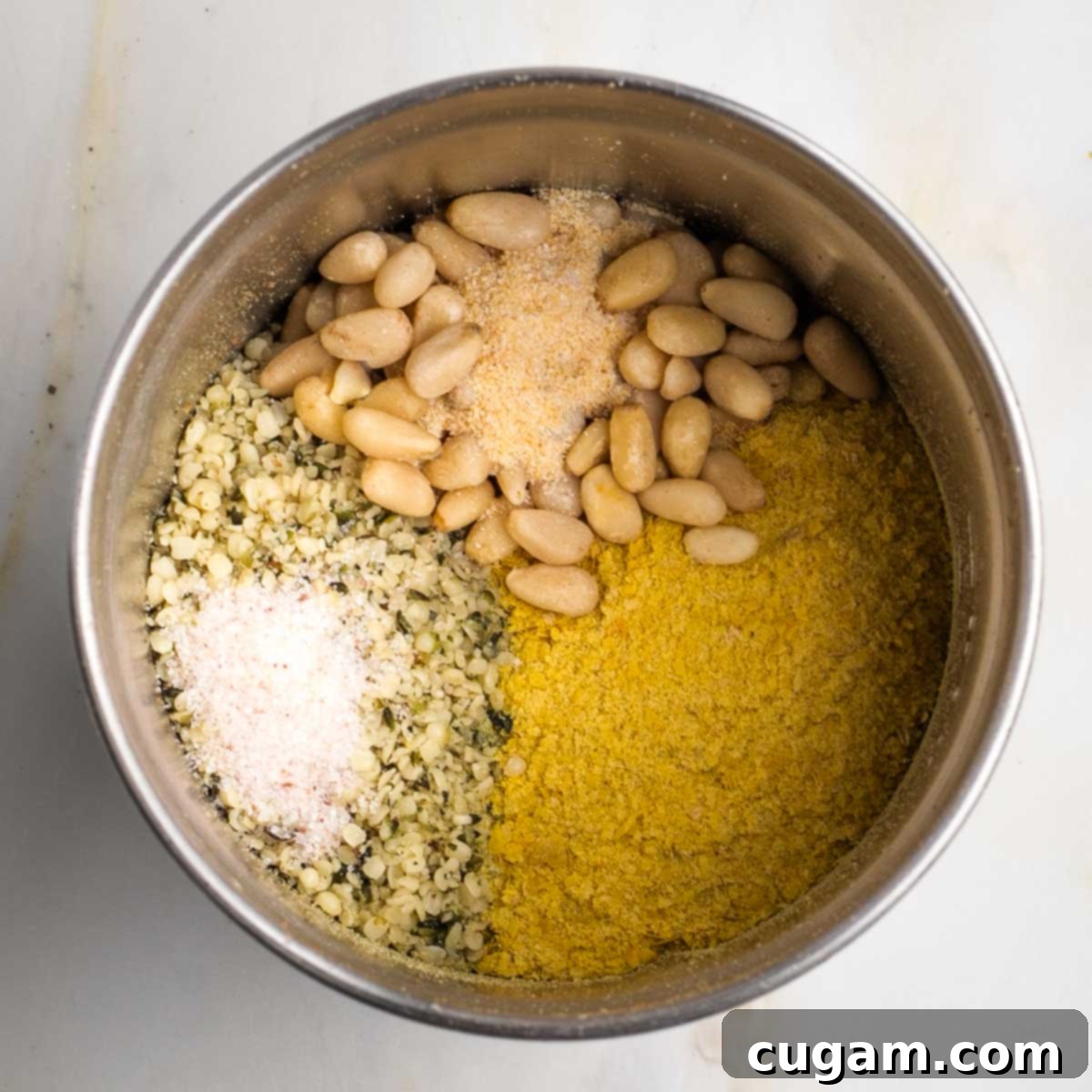 Spice grinder cup filled with hemp seeds, pine nuts, nutritional yeast and spices.