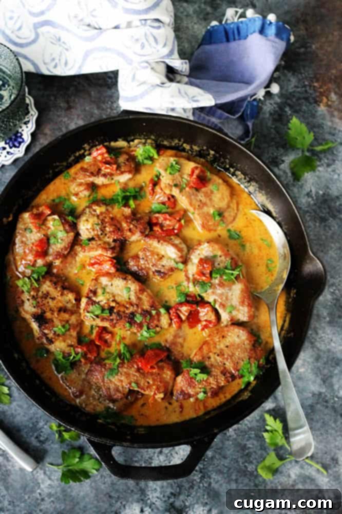 Pork tenderloin medallions in a skillet with creamy sun-dried tomato sauce and fresh parsley