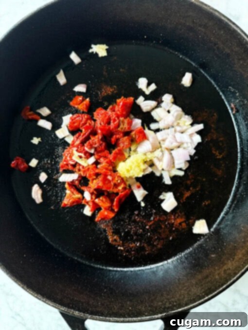 Cooking shallots, garlic, and sun-dried tomatoes in a skillet