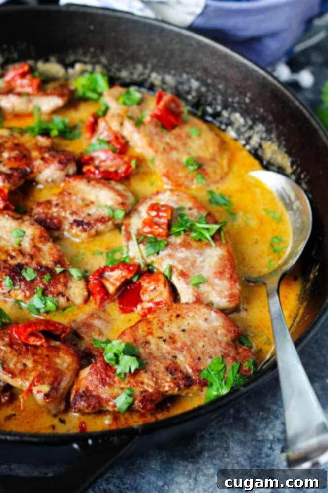 Finished pork tenderloin medallions recipe in a skillet with serving spoon, garnished with fresh parsley.