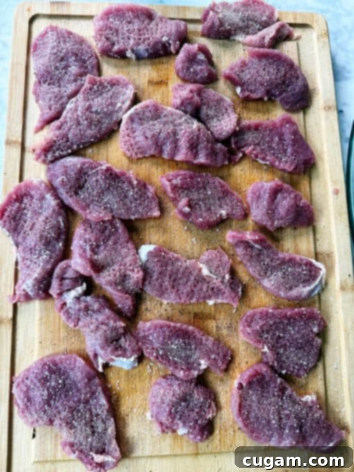 Seasoning pork medallions with salt and pepper on a chopping board