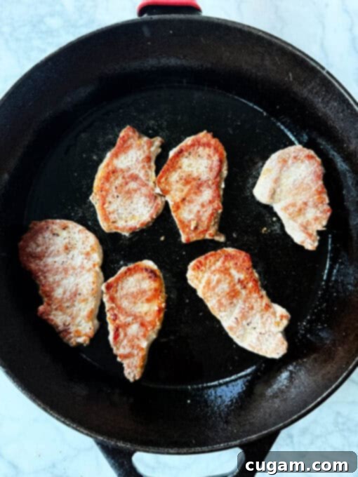 Pork being seared to golden brown perfection in a hot skillet