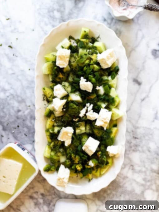 Generous chunks of briny feta cheese are artfully added to the colorful cucumber feta salad, adding creamy texture and salty flavor.