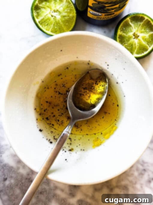 A small white bowl containing the ingredients for the salad dressing: lime juice, salt, pepper, and olive oil, being mixed.