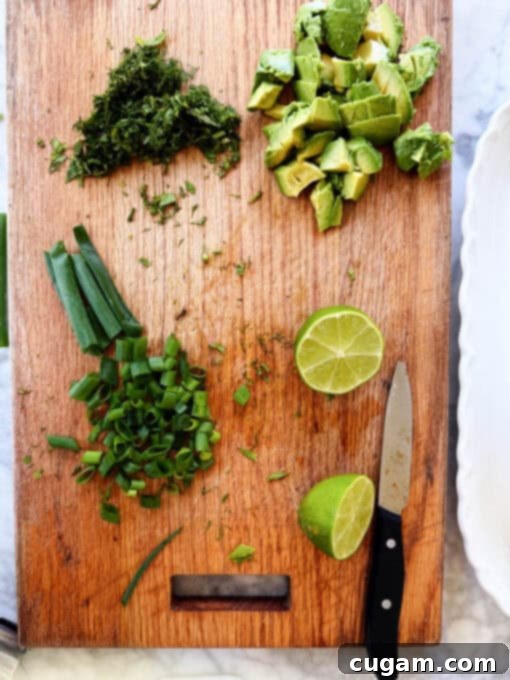 Overhead shot of freshly chopped scallions, fragrant dill, and refreshing mint laid out on a cutting board, ready for the salad assembly.