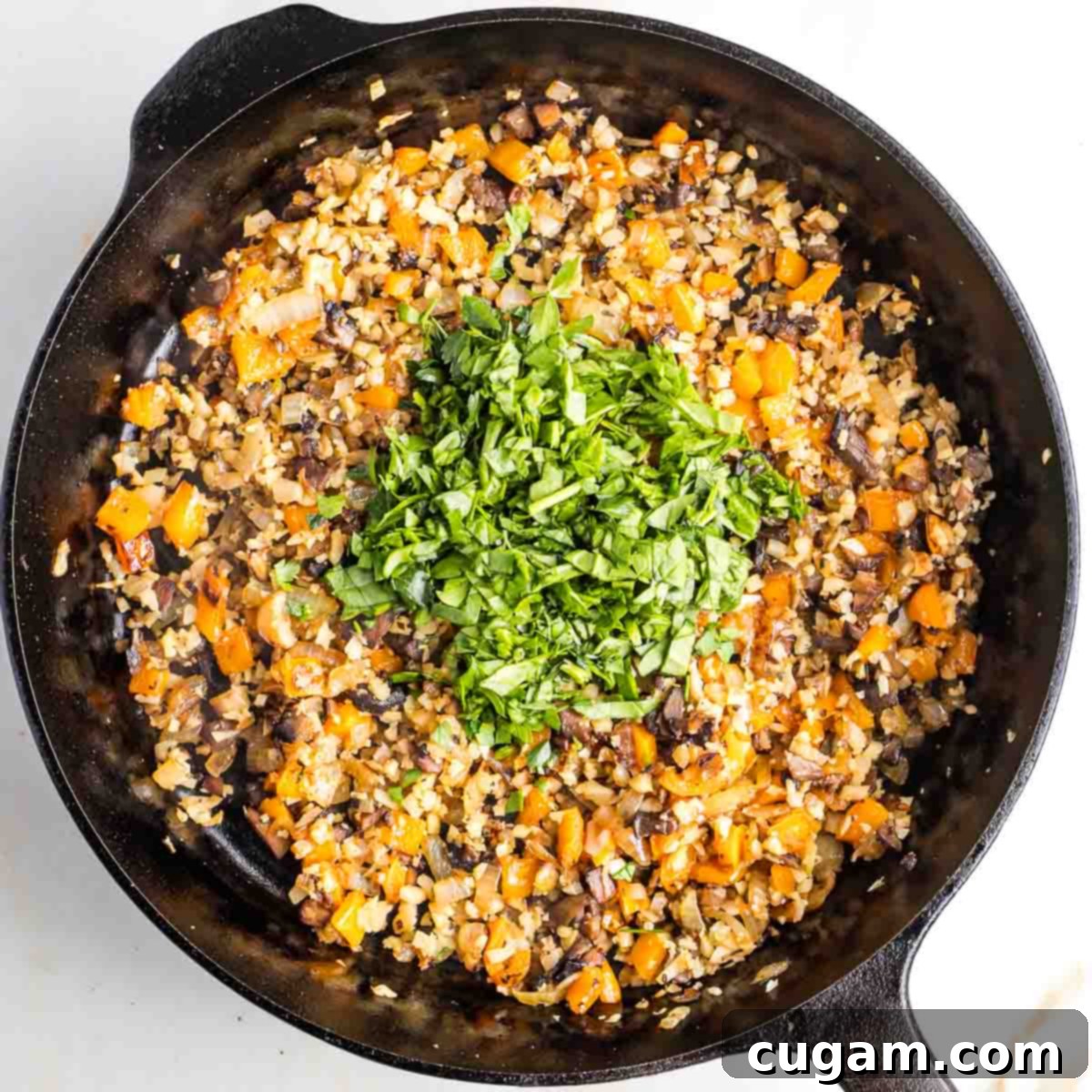 Sauteed small diced vegetables with a heap of chopped greens in the center of the pan.