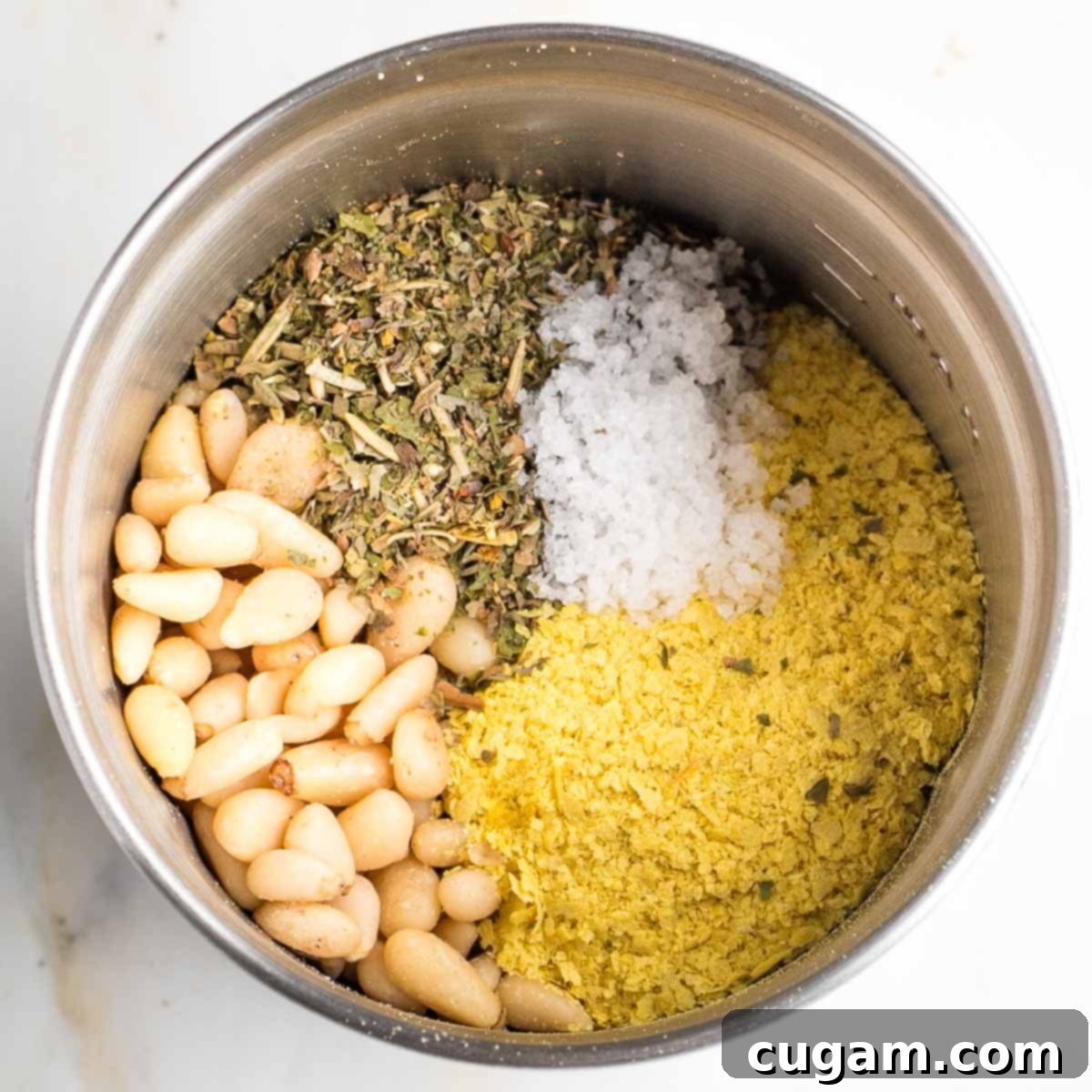 Pine nuts, Italian seasoning, salt and nutritional yeast in the bowl of a spice grinder.