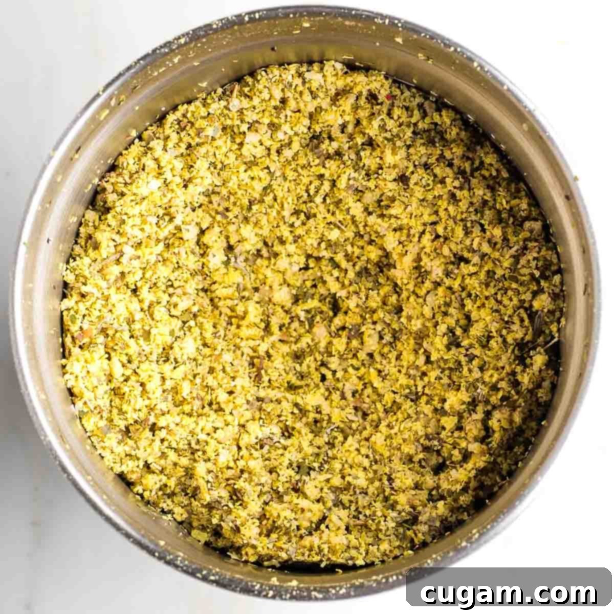 Bowl of a spice grinder filled with yellow coarse ground powder.