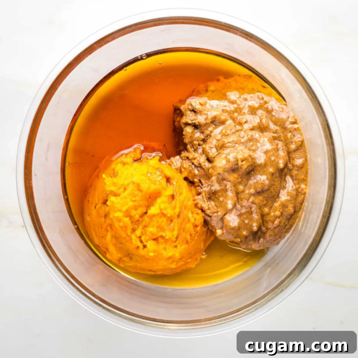 Medium mixing bowl with mashed sweet potatoes, crunchy almond butter and maple syrup.