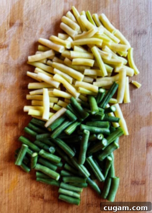 Chopped yellow and green string beans on a cutting board, ready to be added