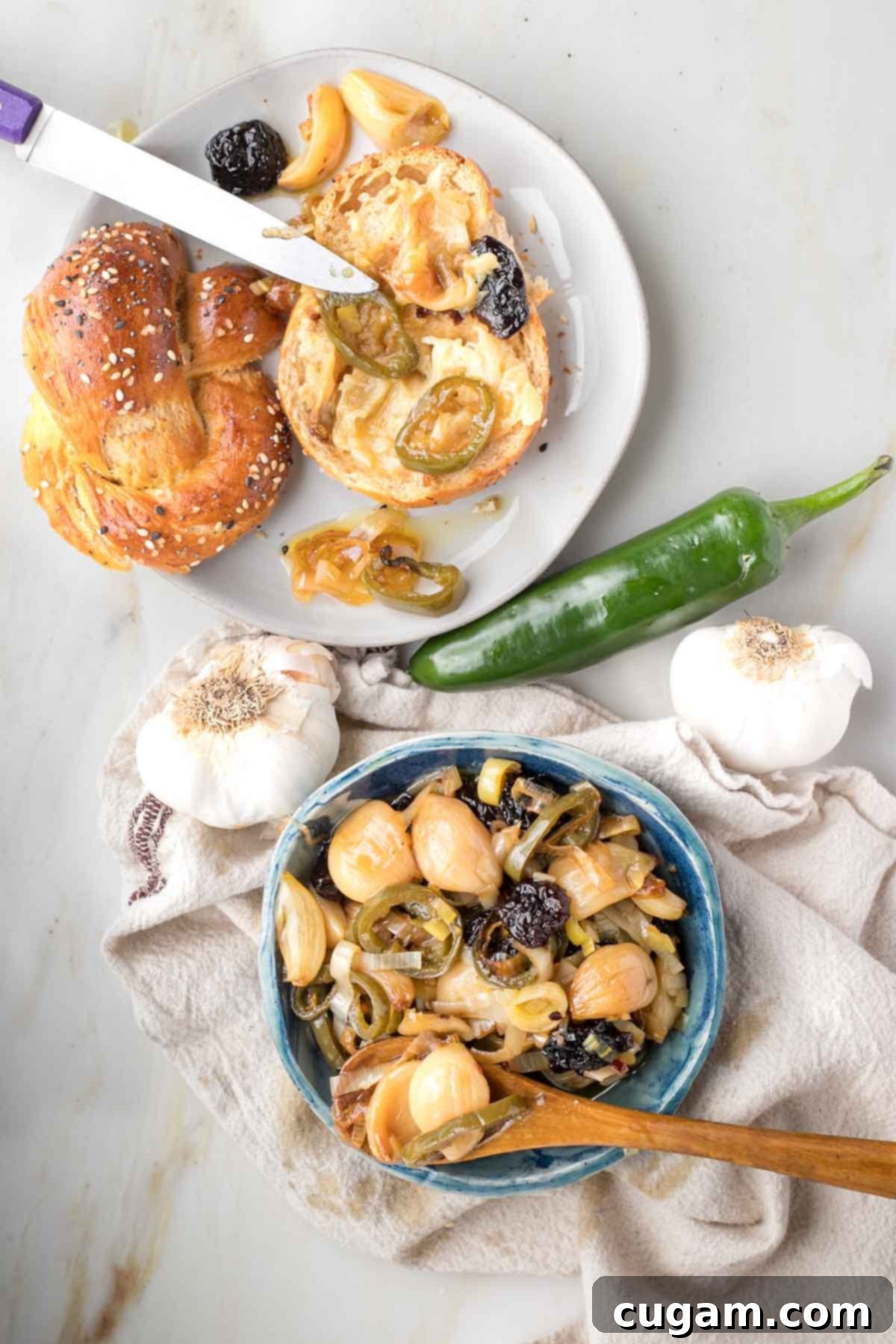 Challah roll spread with garlic confit plus a bowl with garlic, leeks, cherries and jalapenos made into confit. 