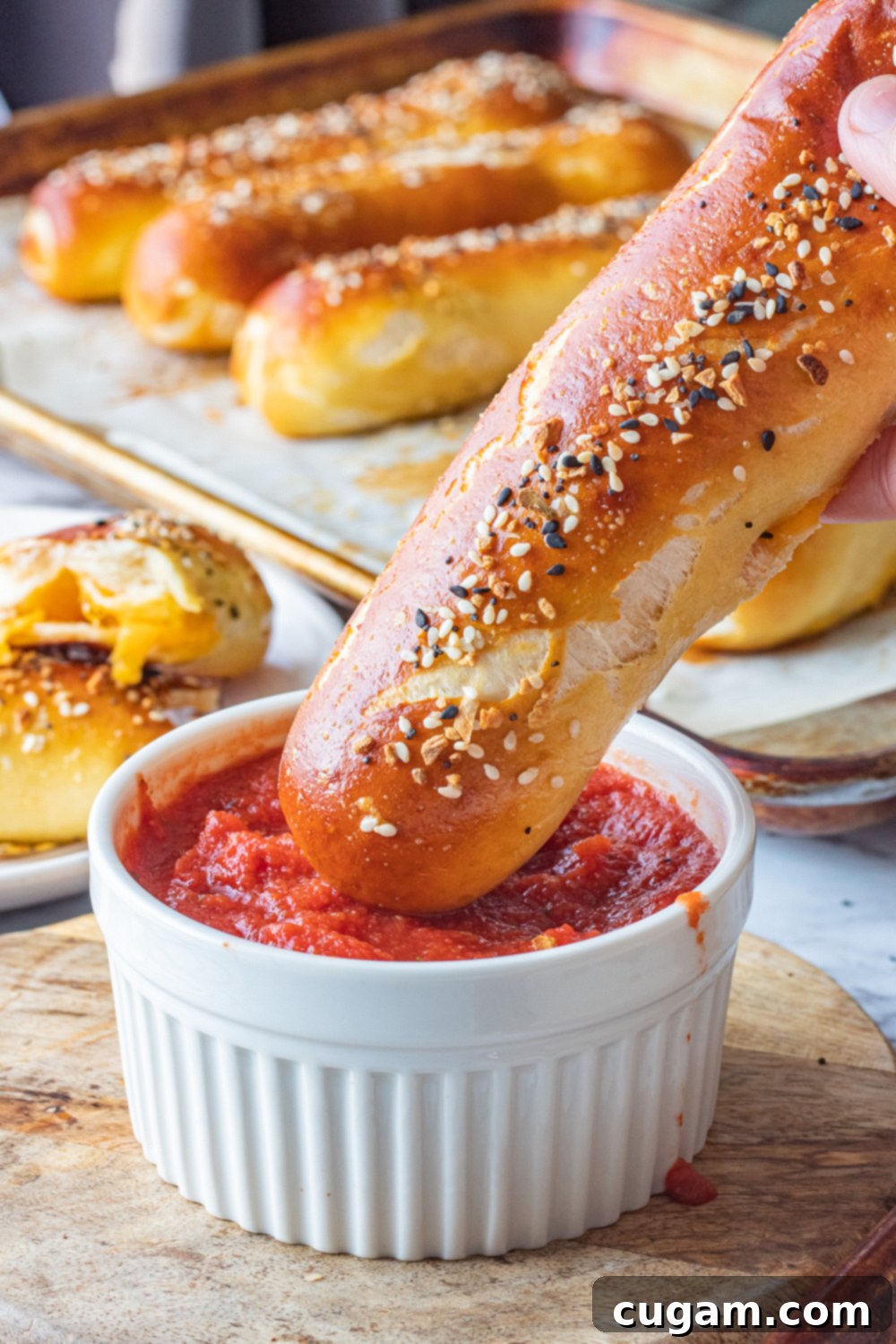 Baked cheese pretzel above tomato sauce in white bowl. 