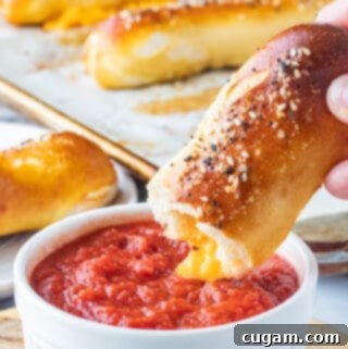 baked cheese pretzel above white bowl of pizza sauce.