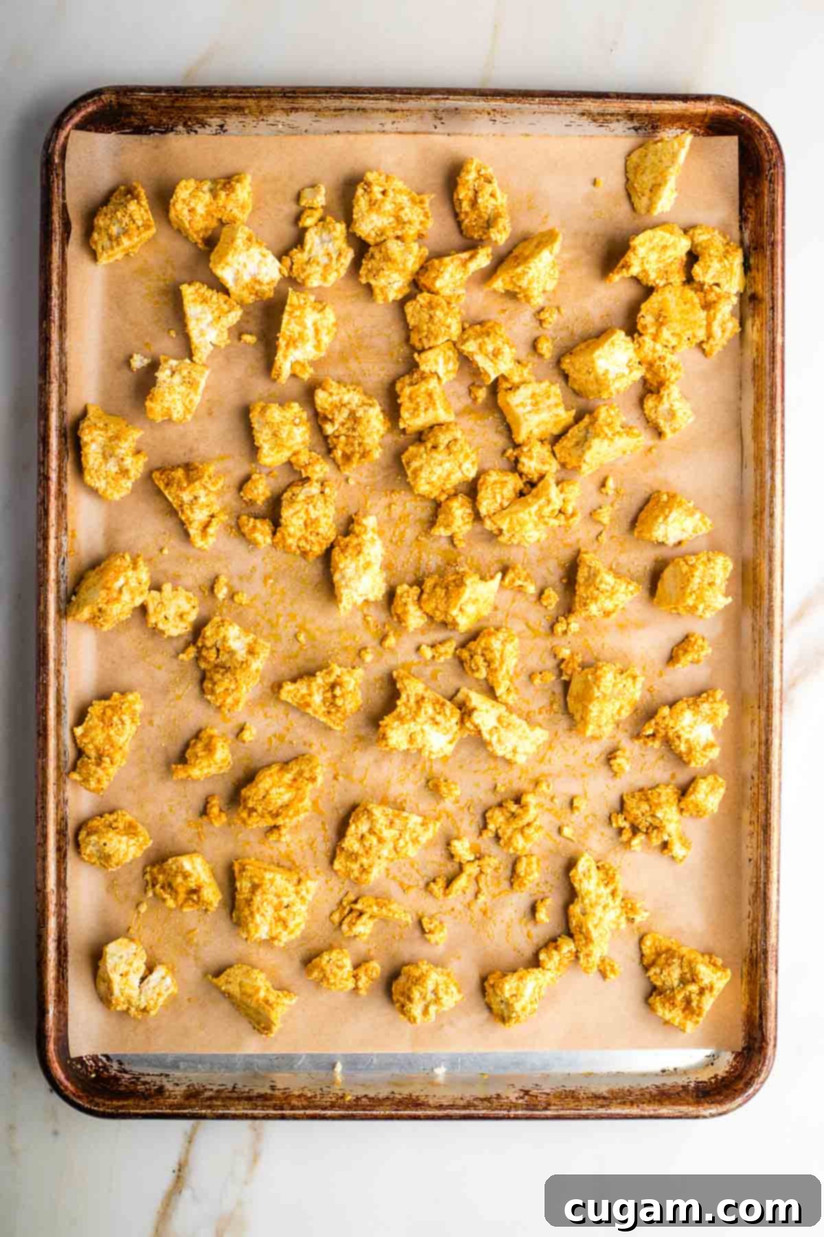Tofu pieces tossed with marinade on a baking sheet.