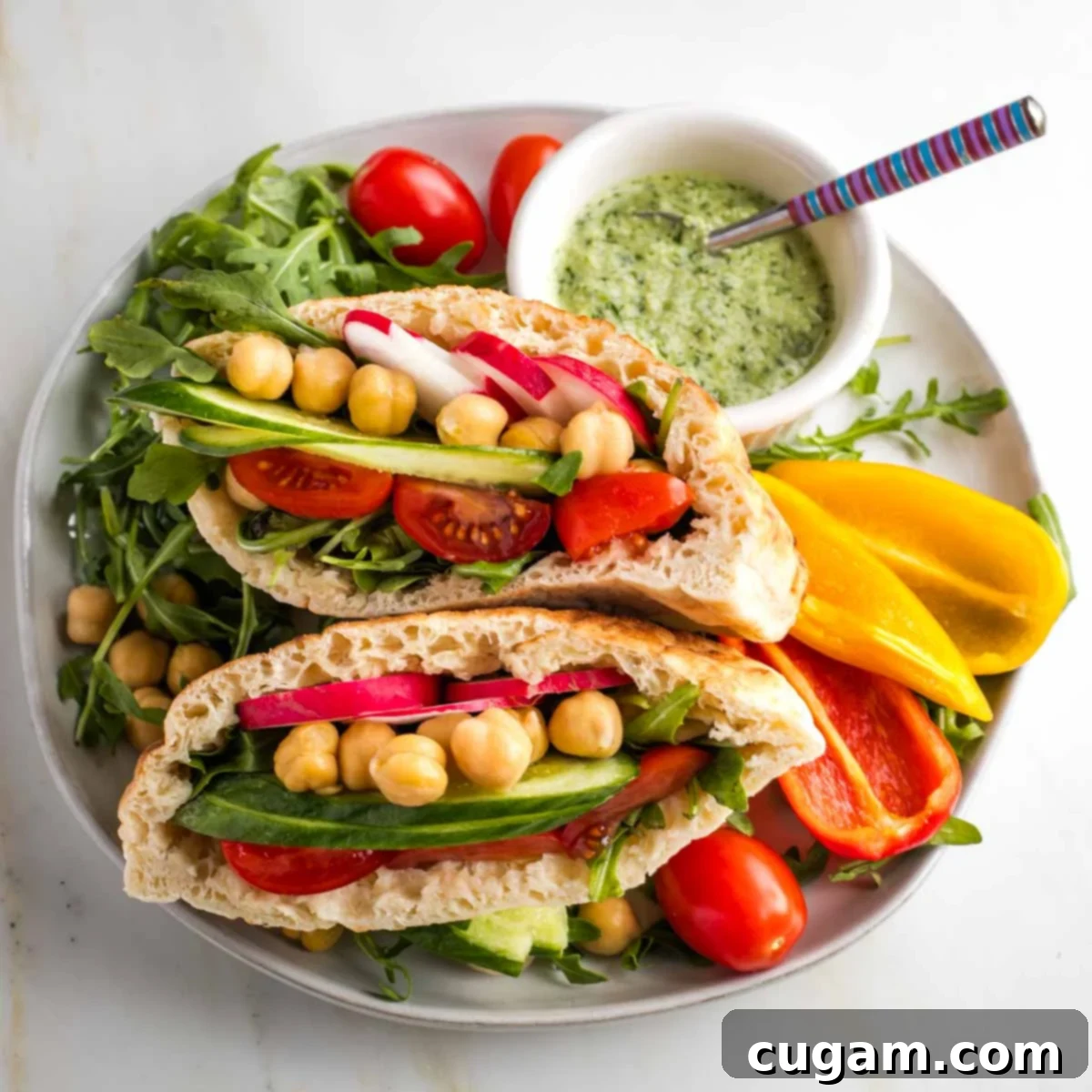 Pita halves filled with fresh vegetables with a side of dairy-free tzatziki sauce.