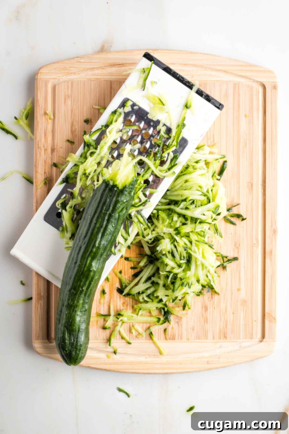 Box grater, shredding a cucumber. 