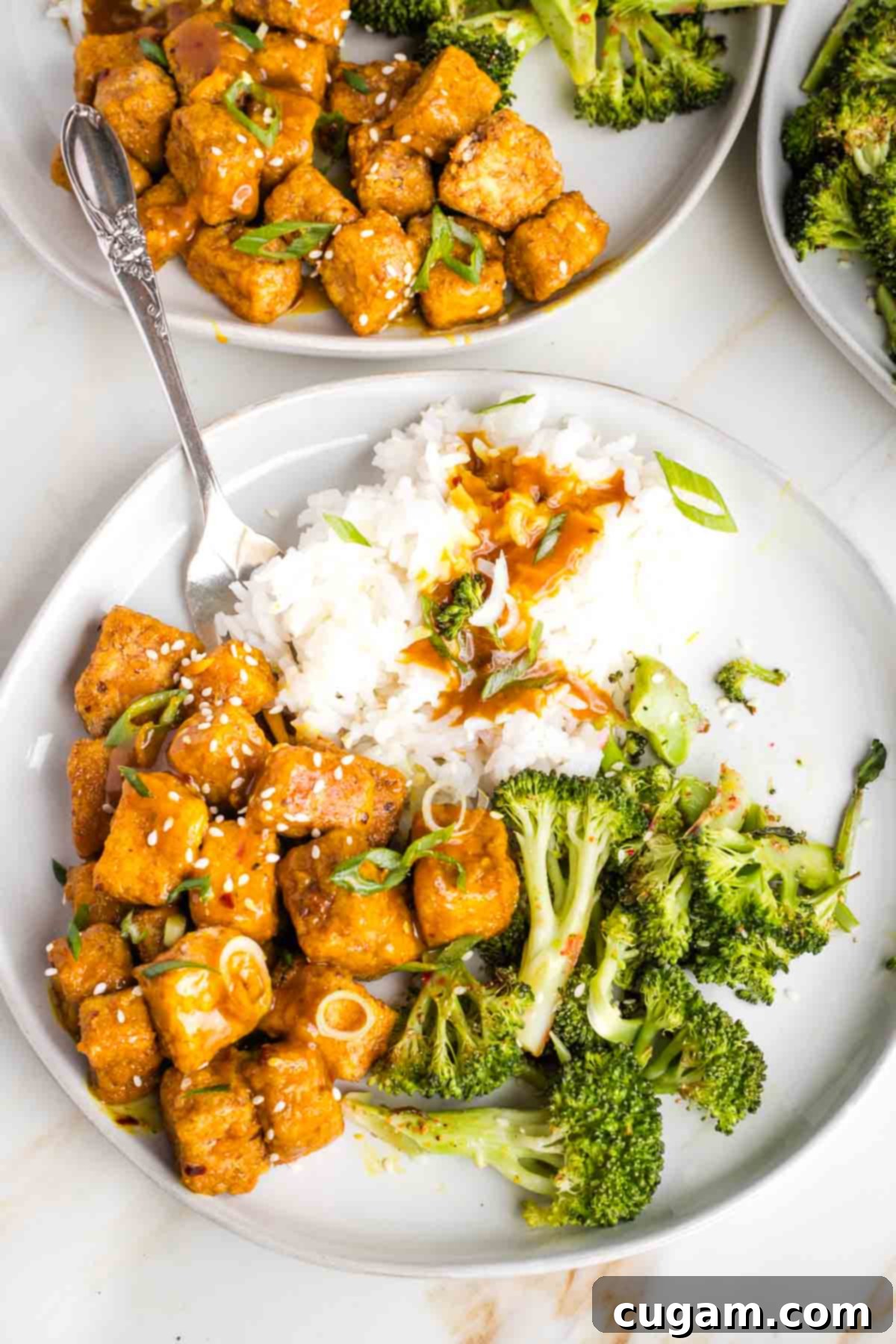 Plate of orange tofu, white rice and roasted broccoli. 