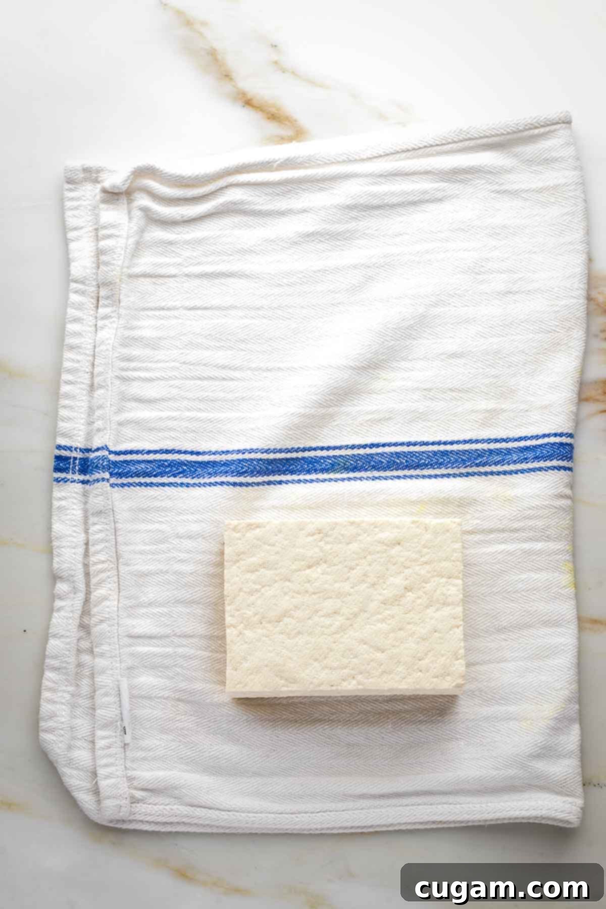 Block of tofu on a kitchen towel.