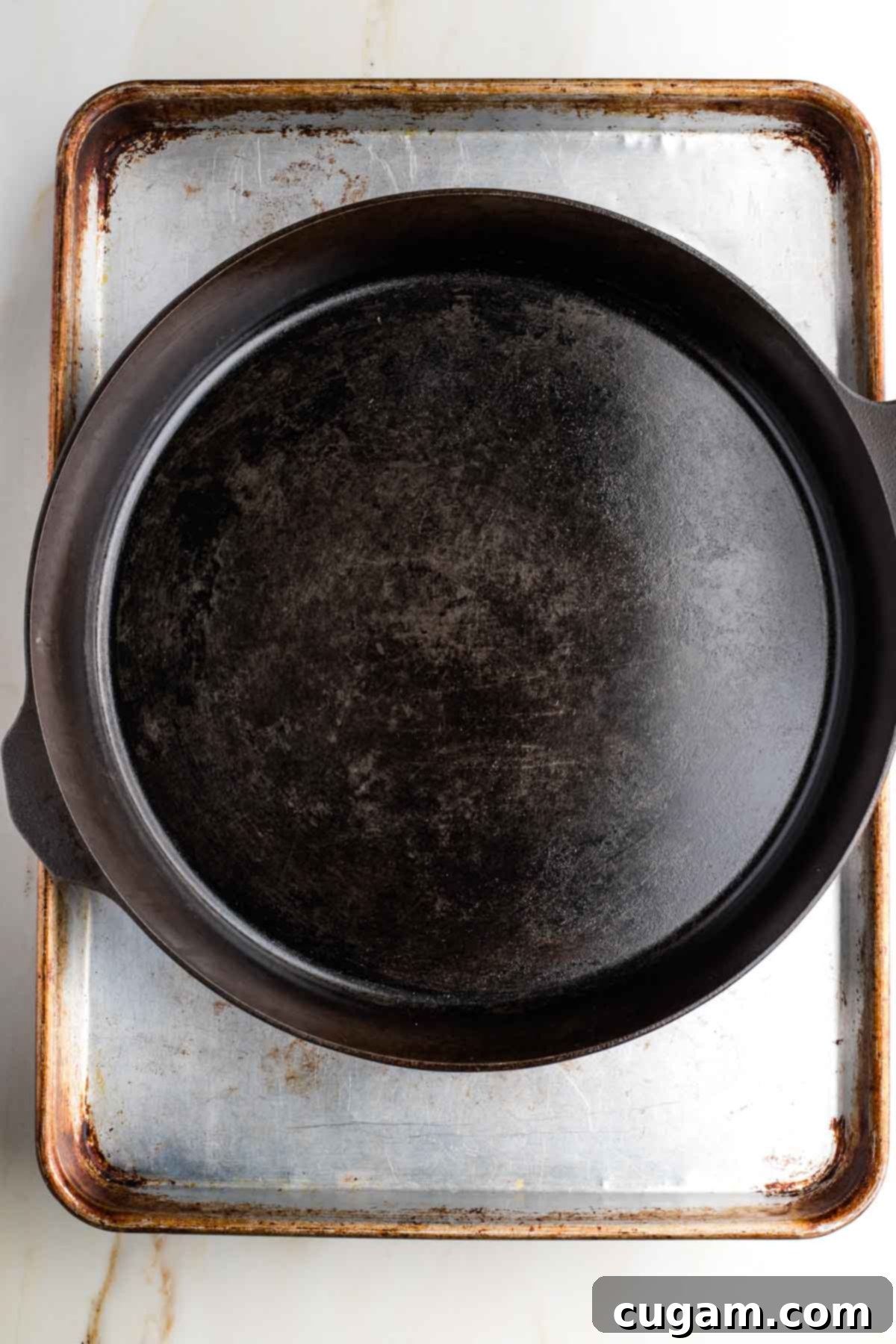 Cast iron skillet on top of a half sheet pan.